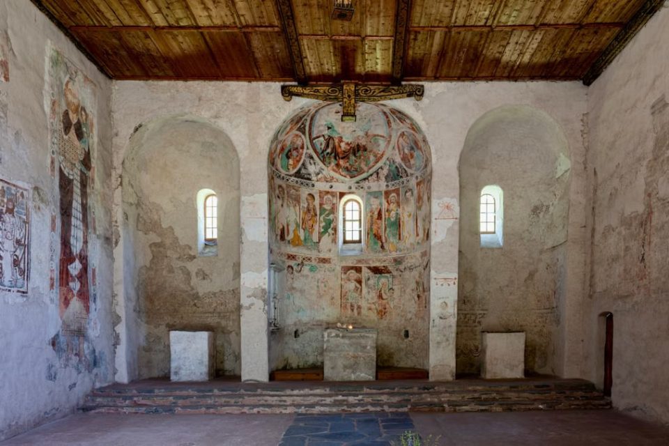 Interior of ancient church showcasing historic frescoes and stone architecture.
